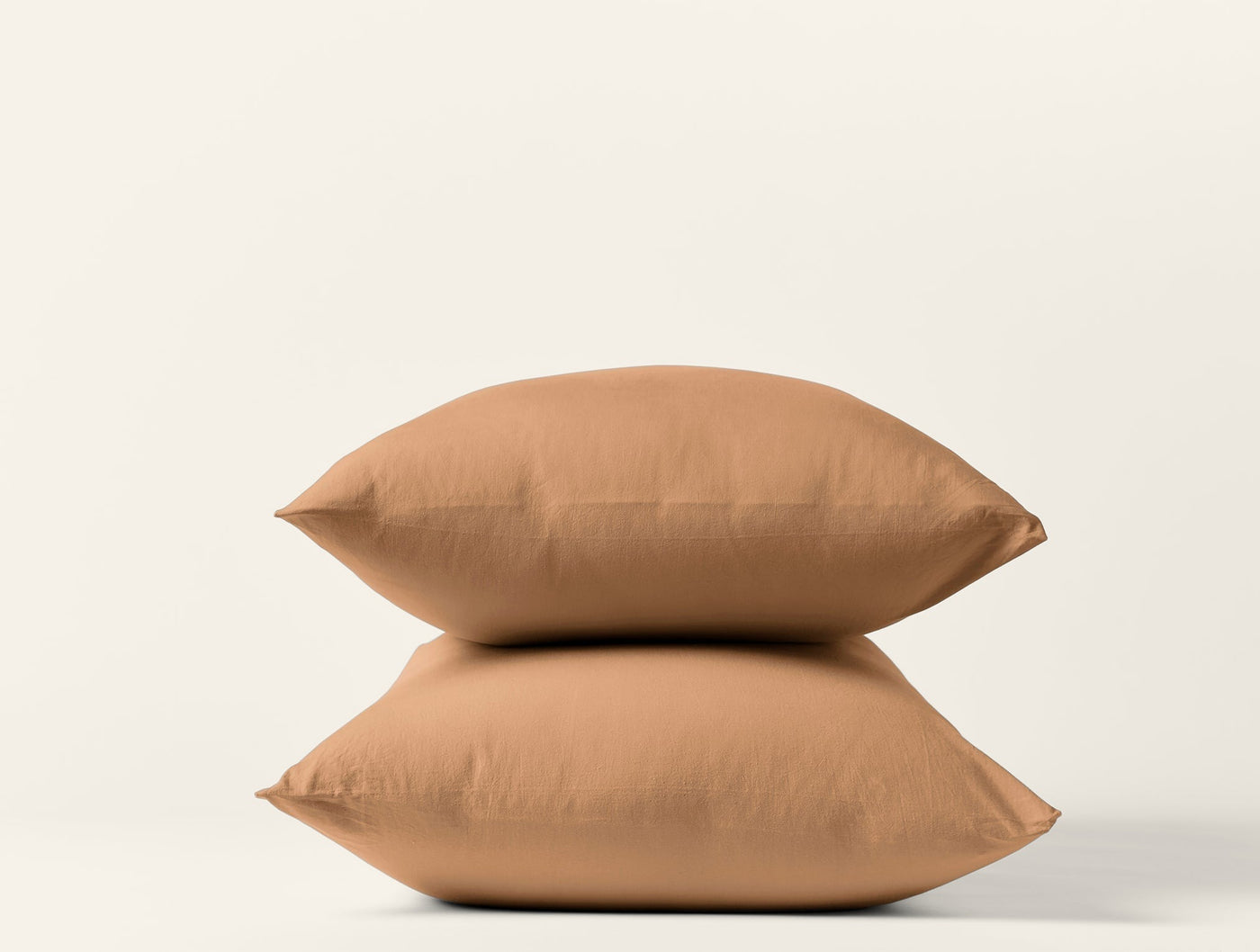 Two caramel Coyuchi Crinkled Percale pillowcases stacked against a white background.