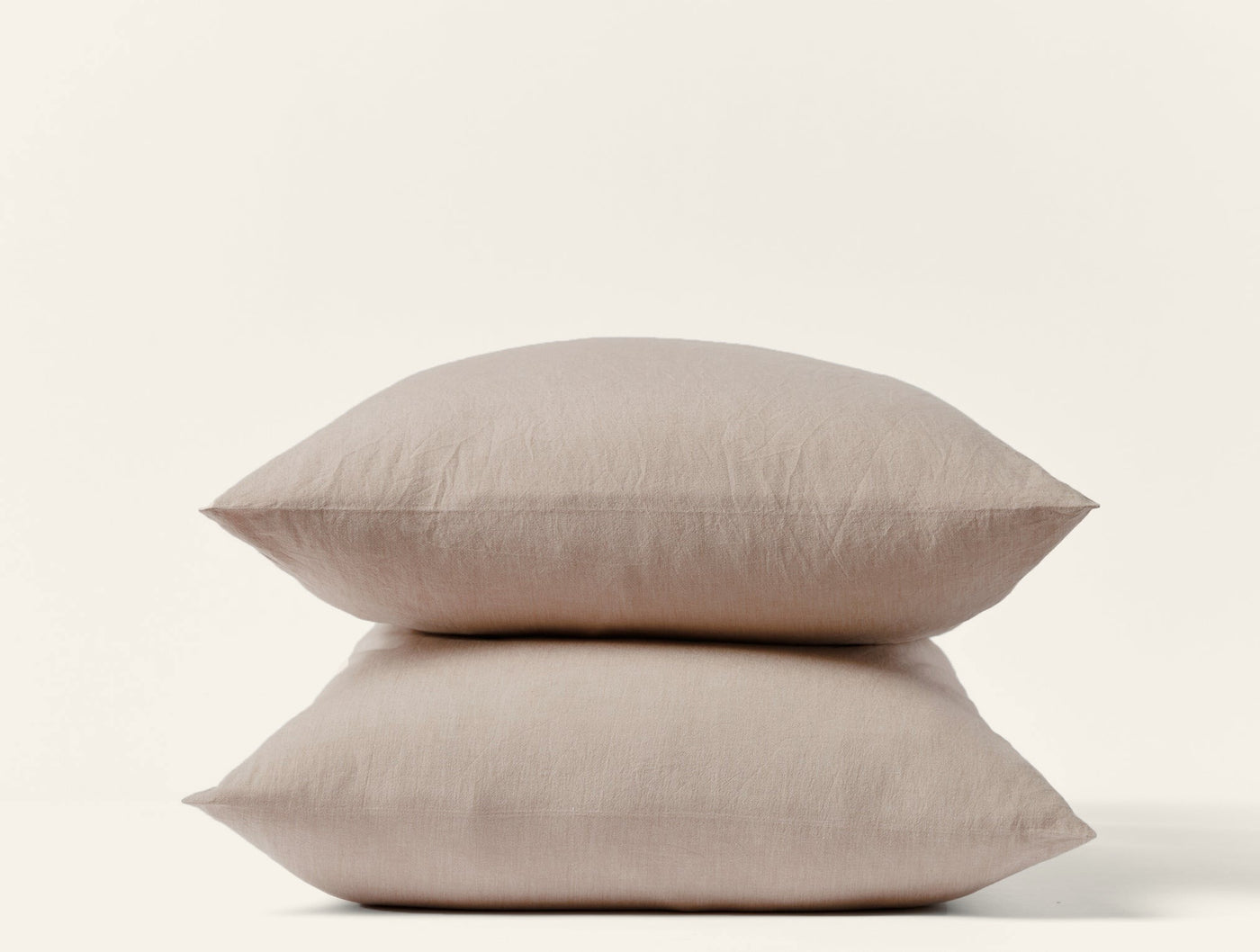 Two stacked dune Coyuchi Crinkled Percale pillowcases showing relaxed texture on white background.