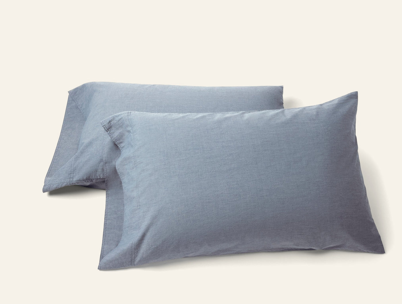 Two slate blue Coyuchi Crinkled Percale pillowcases with subtle texture, stacked on white background.