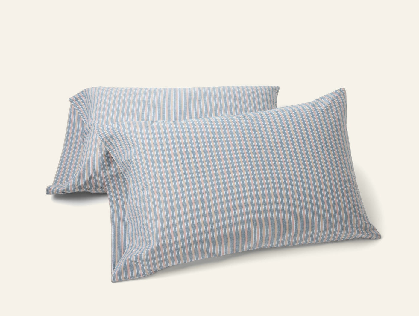 Two Coyuchi Crinkled Percale pillowcases with blue and pink thin stripes on white.