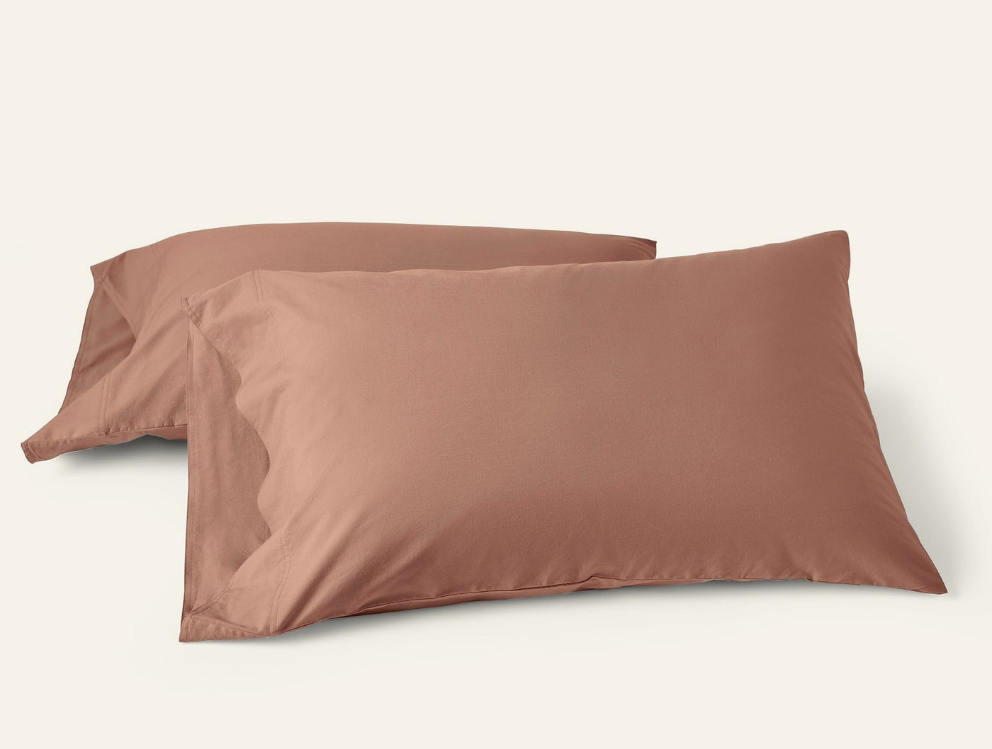 Two Coyuchi Crinkled Percale pillowcases in terracotta, stacked on a white background.