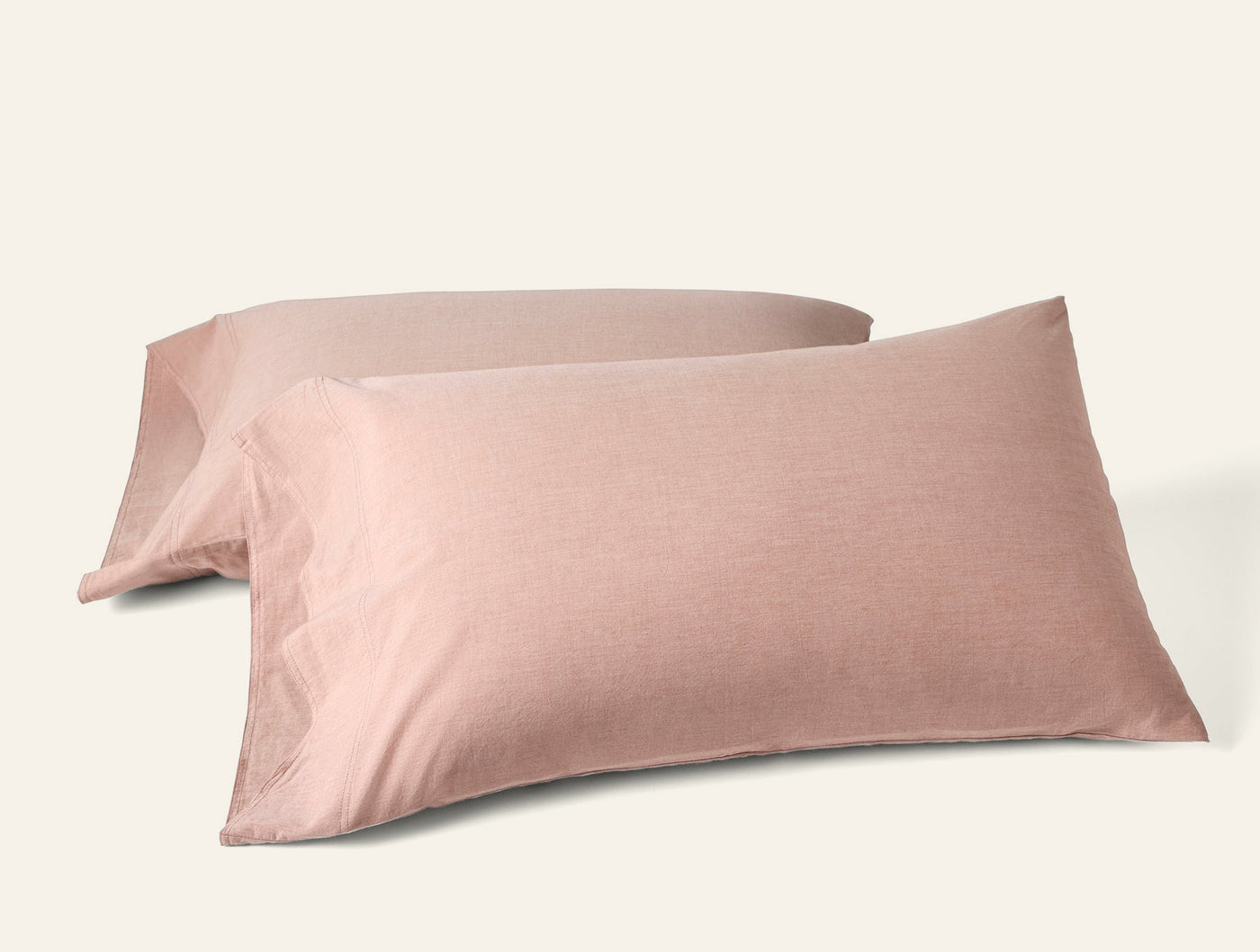 Two blush pink Coyuchi Crinkled Percale pillowcases stacked at an angle on white background.