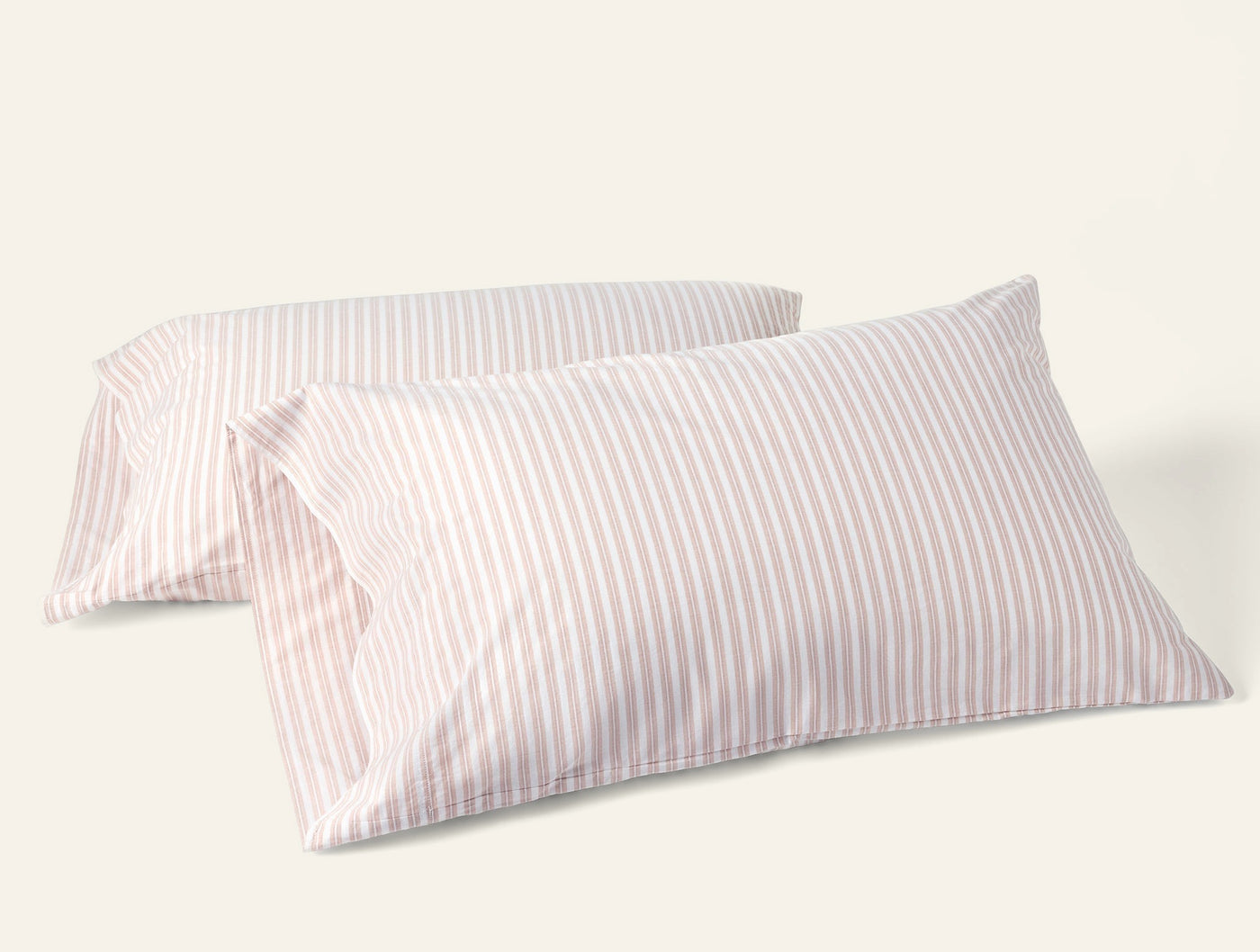 Pair of Coyuchi Crinkled Percale pillowcases in blush and white narrow stripes.
