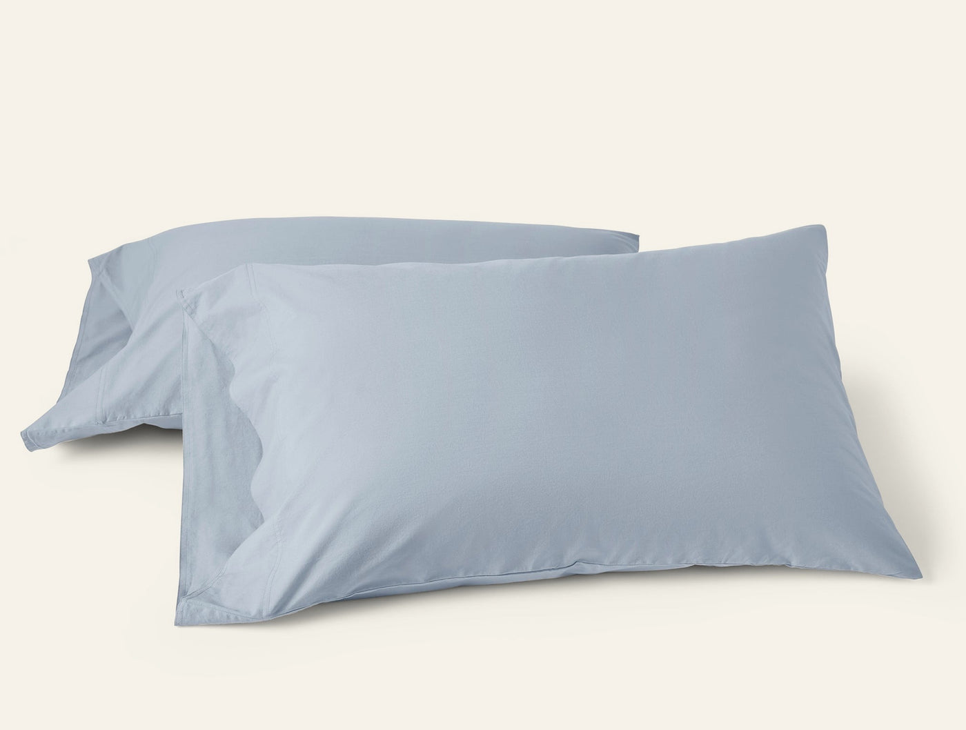Two mist blue Coyuchi Crinkled Percale pillowcases, overlapping on white background.