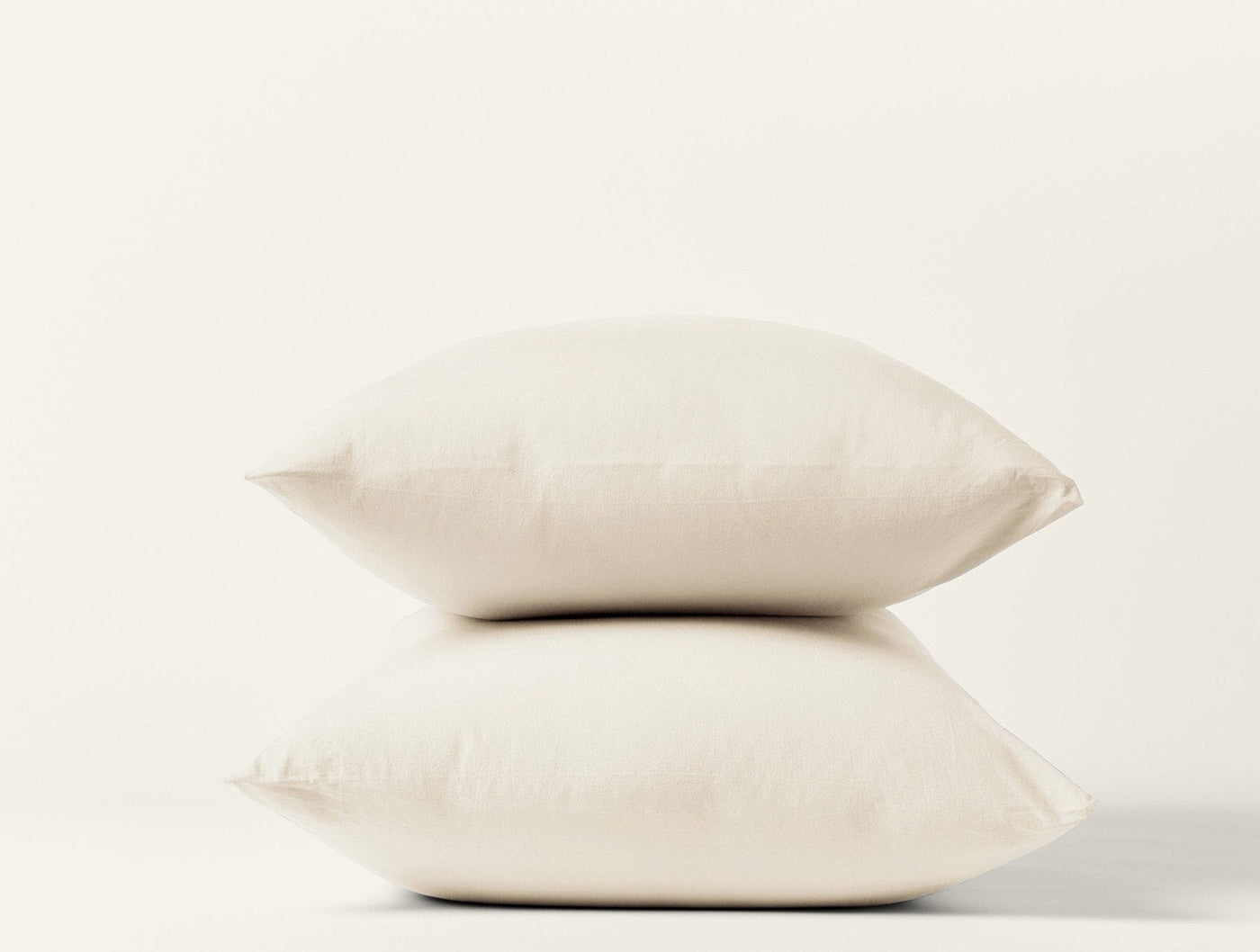 Two stacked ivory Coyuchi Crinkled Percale pillowcases against a white background.