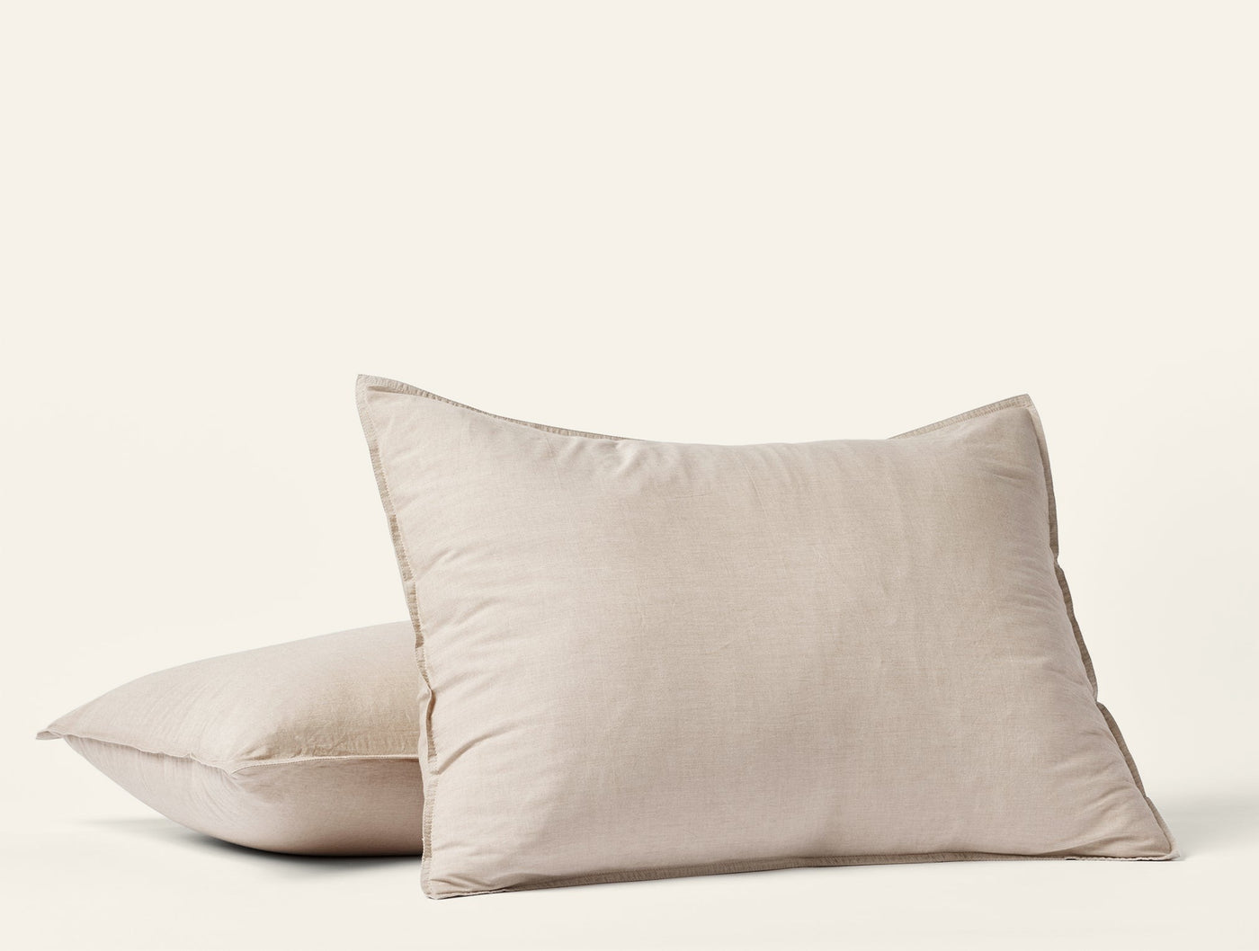 Close-up of two stacked Coyuchi Crinkled Percale pillow shams in natural linen tone.