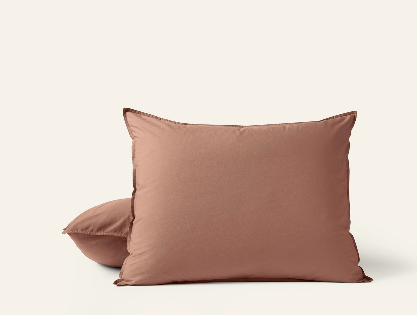 Two terracotta Coyuchi Crinkled Percale pillow shams stacked against a white background.