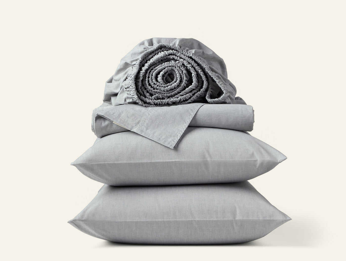 Dove grey crinkled percale sheet set stacked with rolled fitted sheet on top.