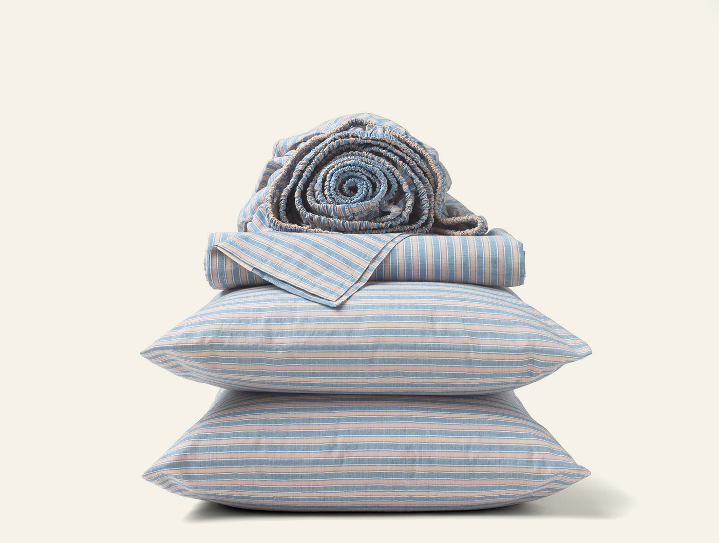 Two blue and white striped percale pillowcases stacked with folded and rolled matching sheets.