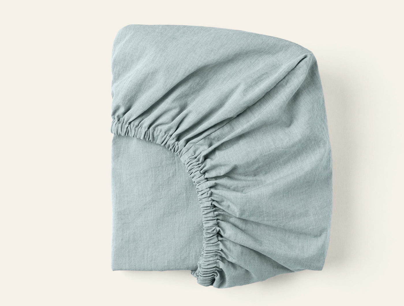 Coyuchi Crinkled Percale fitted sheet folded, showing elasticized corner in mist blue.