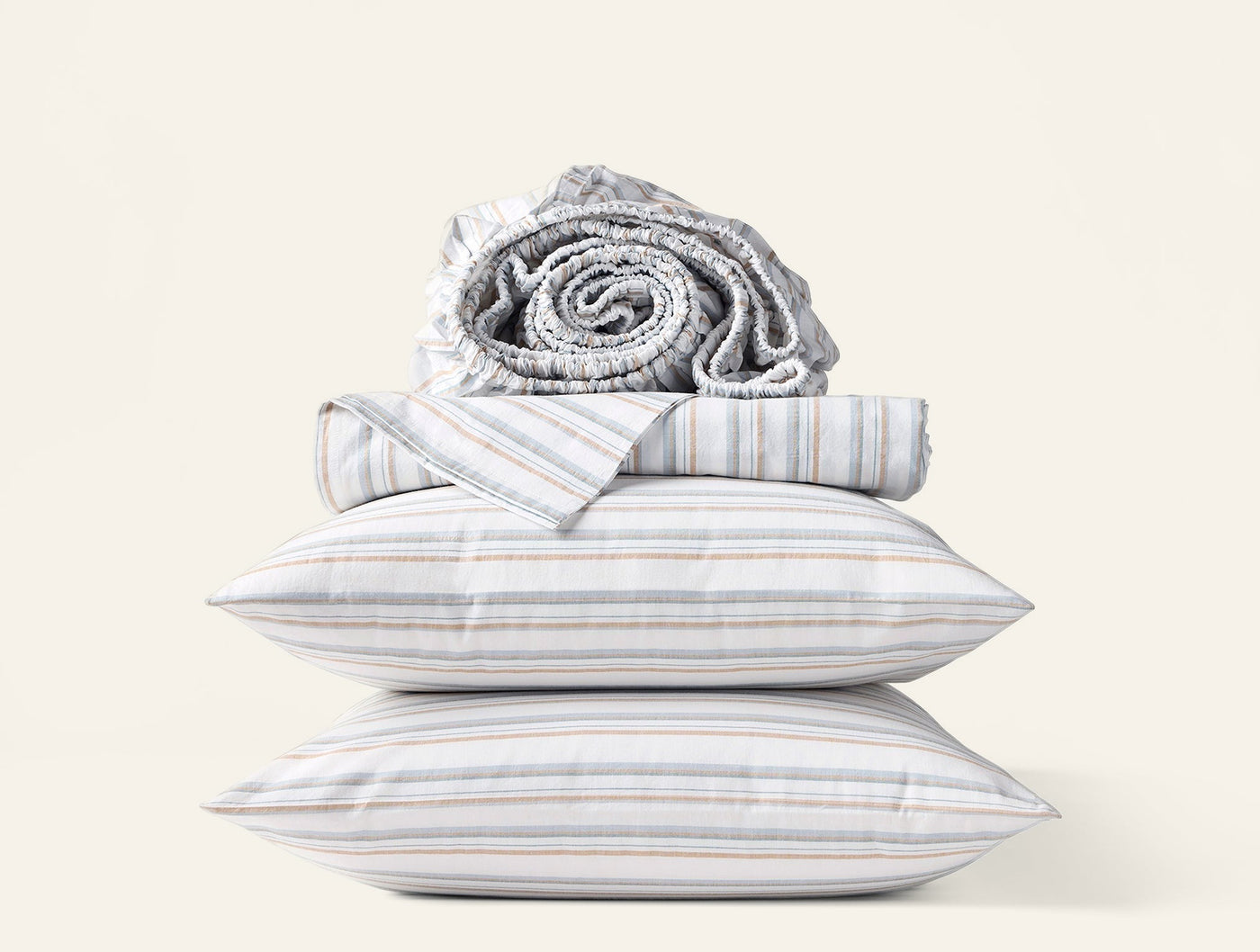 Stacked Coyuchi Crinkled Percale sheet set with multicolor stripe pillowcases and rolled sheets.