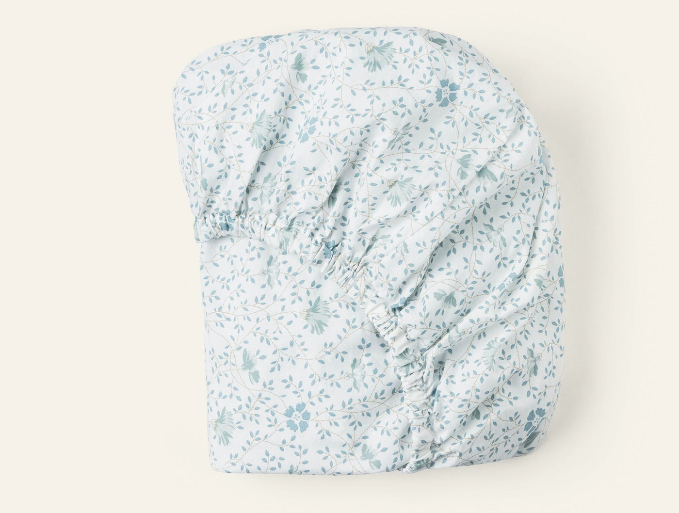 Close-up of Coyuchi fitted sheet corners with blue floral percale print on white.
