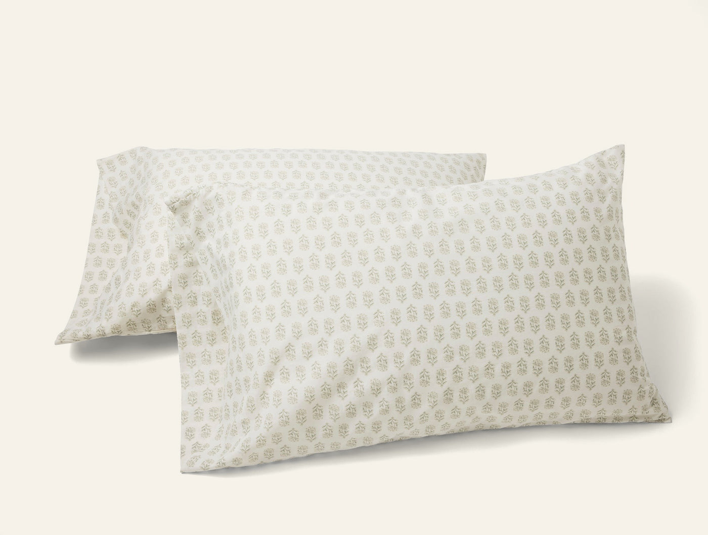 Pair of Coyuchi ivory percale pillowcases with sage botanical block print pattern.