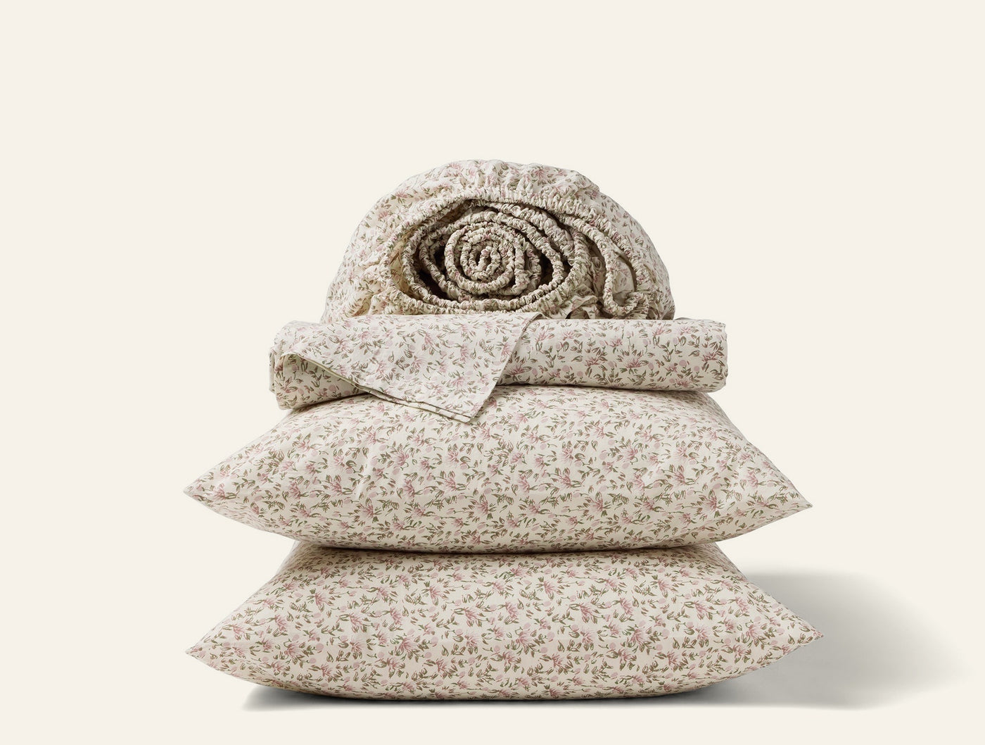 Close-up stack of Coyuchi Print Percale sheet set with delicate floral pattern in ivory.