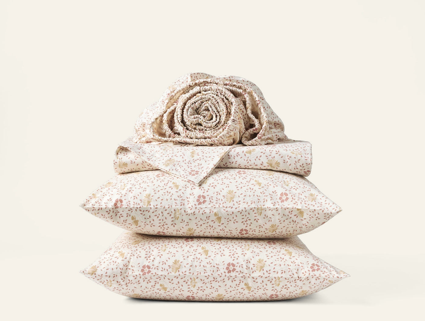 Close-up of stacked Coyuchi Print Percale sheet set in ivory with delicate floral print.