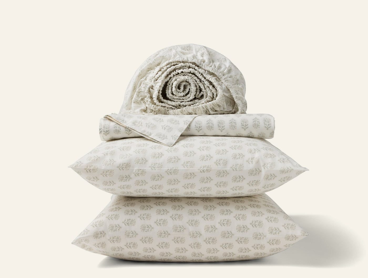 Close-up stack of Coyuchi Print Percale sheet set in ivory with subtle botanical print.