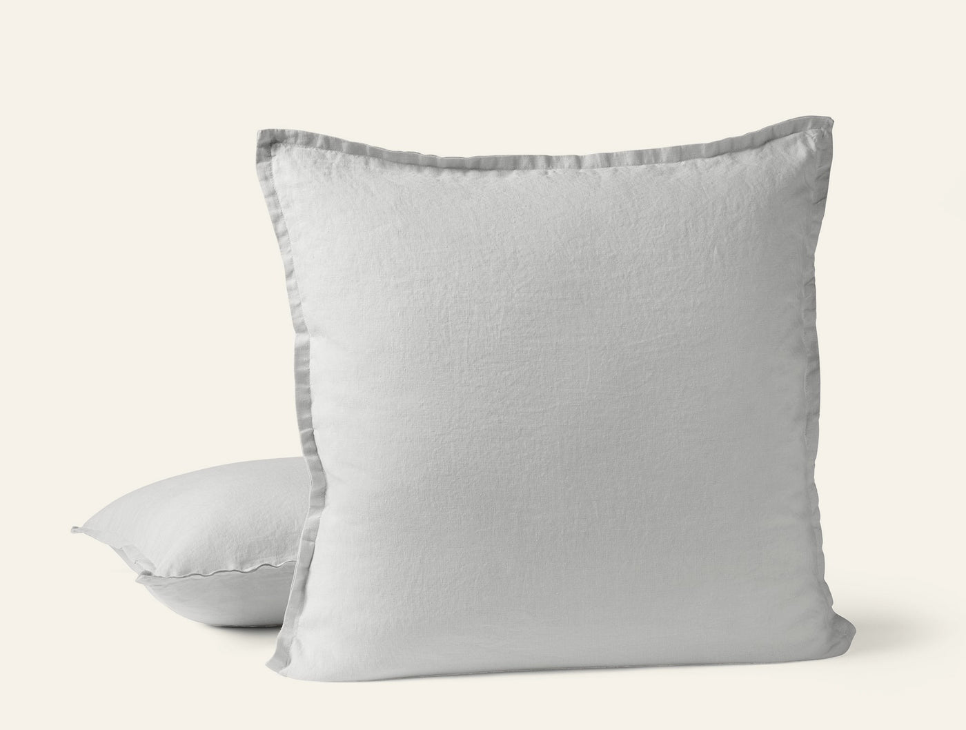 Two white Coyuchi Relaxed Linen pillow covers, front pillow showing gray flange trim detail.