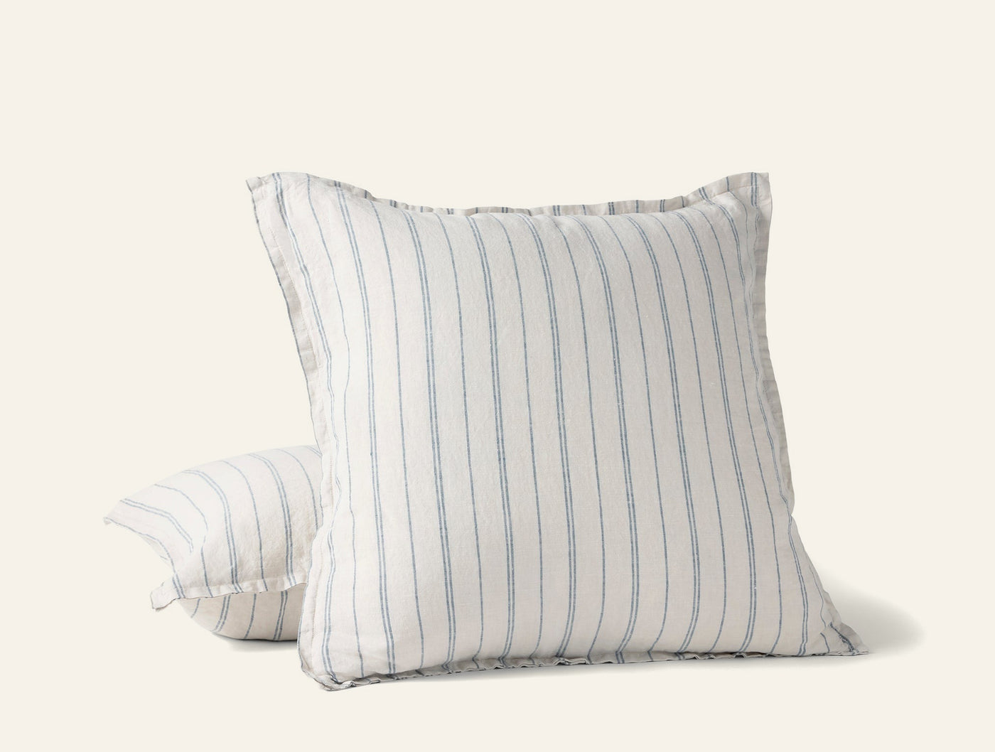 Close-up of Coyuchi Relaxed Linen pillow covers in white with blue pinstripes, ruffled edges.