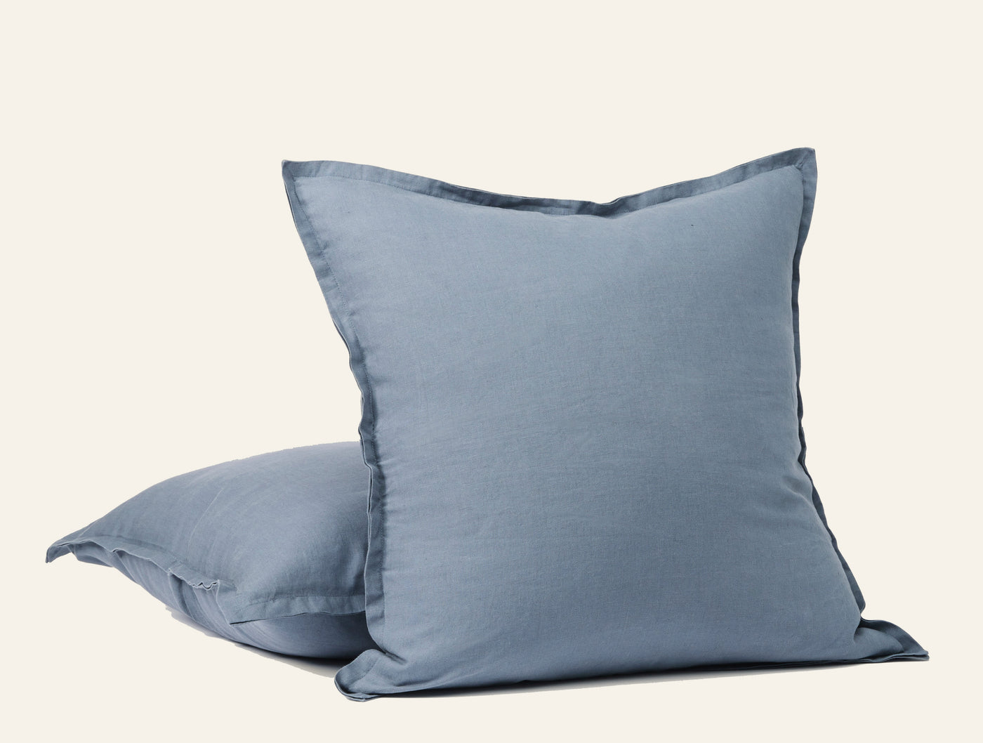 Pair of Coyuchi Relaxed Linen decorative pillows in slate blue, flanged edges, stacked arrangement.