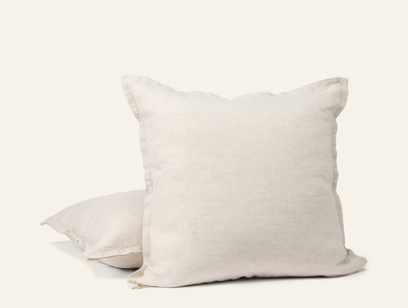 Two Coyuchi Relaxed Linen ivory pillow covers stacked, showing flange edge detail.