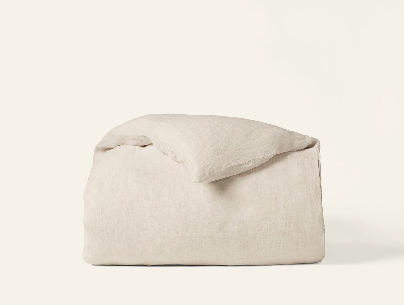 Coyuchi Relaxed Linen duvet cover in natural, folded with pillow on white background.