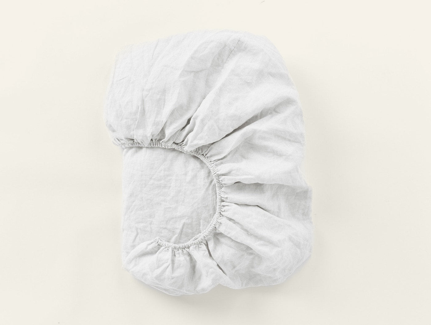 Coyuchi Relaxed Linen fitted sheet in white, folded to show elasticated corner detail.