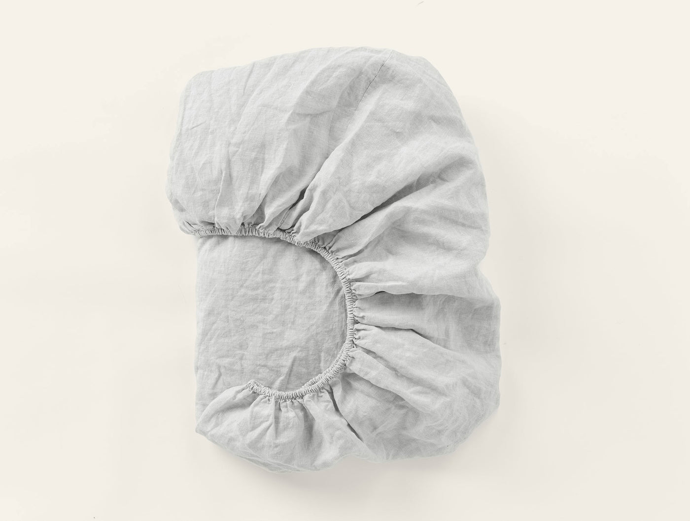 Folded silver Coyuchi Relaxed Linen fitted sheet showing elasticized corner detail.