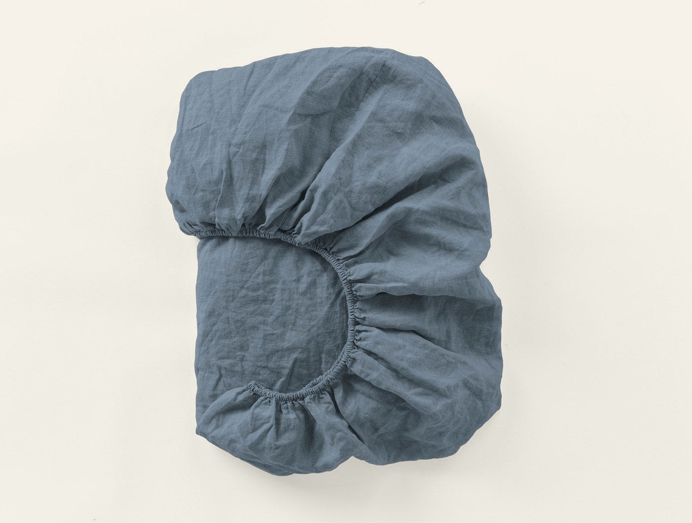 Coyuchi Relaxed Linen fitted sheet in slate blue, folded to show elasticated corner.