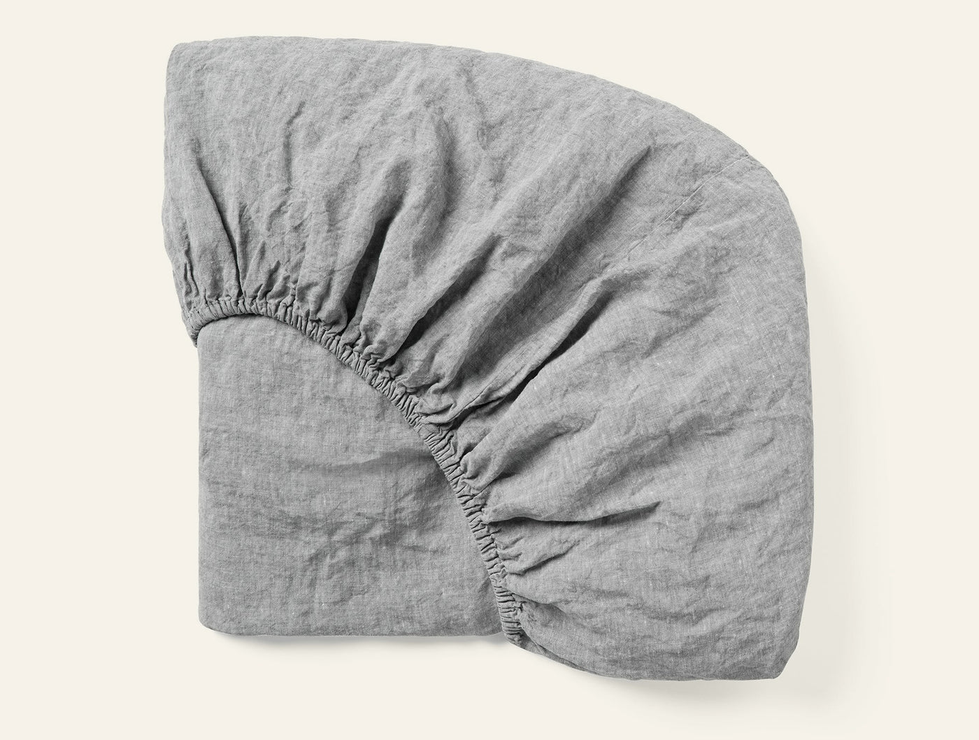 Corner detail of Coyuchi Relaxed Linen fitted sheet in grey showing elastic and drape.