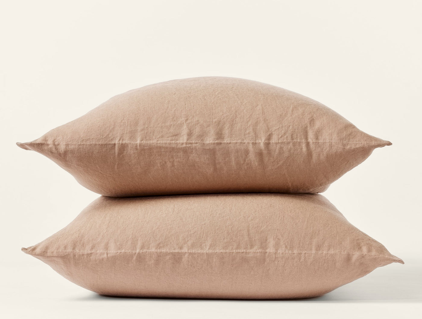 Two stacked Coyuchi Relaxed Linen pillowcases in warm tan, showing natural wrinkled texture.