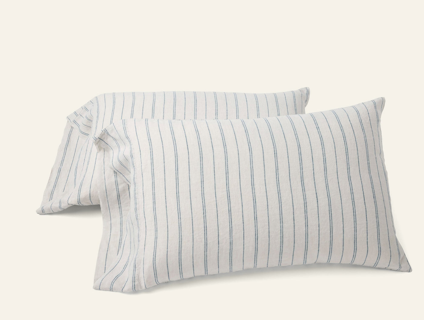 Pair of Coyuchi Relaxed Linen pillowcases with blue pencil stripes on ivory, stacked at an angle.