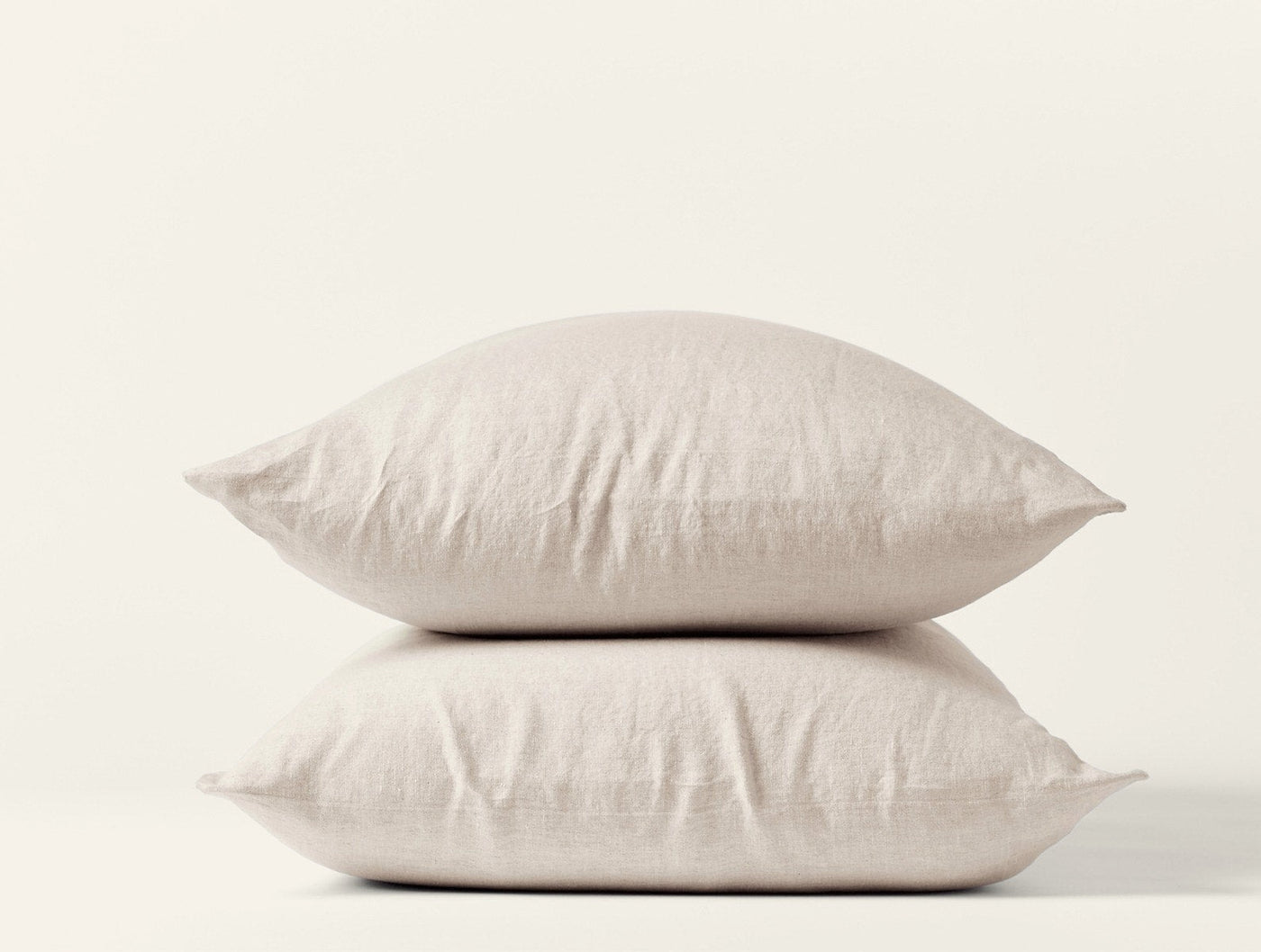 Two stacked Coyuchi Relaxed Linen pillowcases in natural, showing soft drape and woven texture.