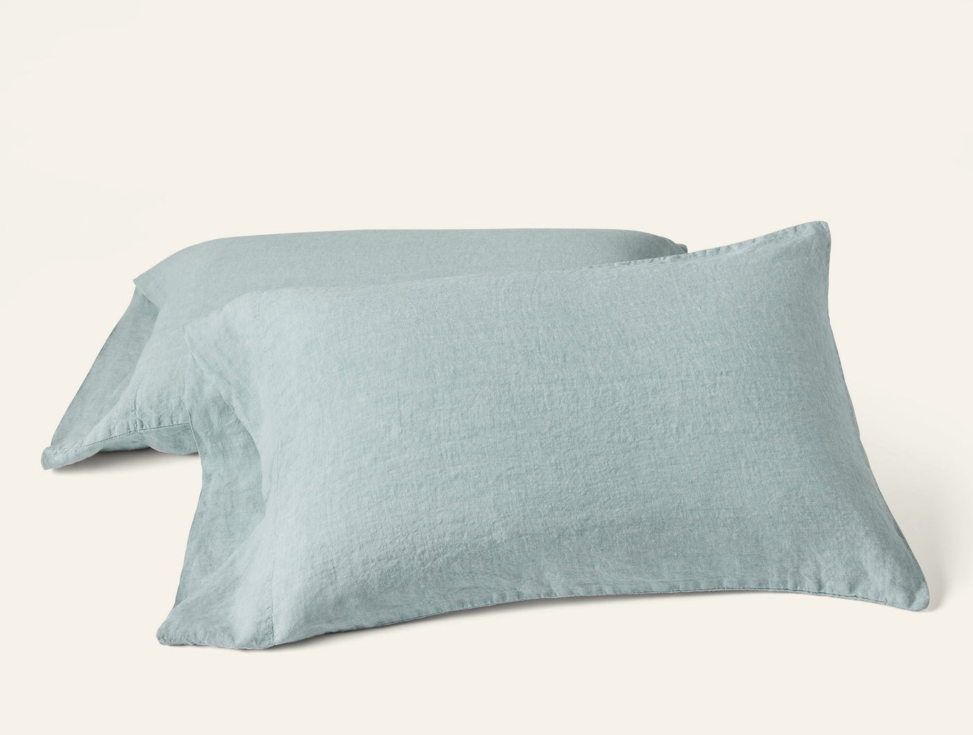 Two Coyuchi Relaxed Linen pillowcases in mist blue, stacked at an angle on white background.
