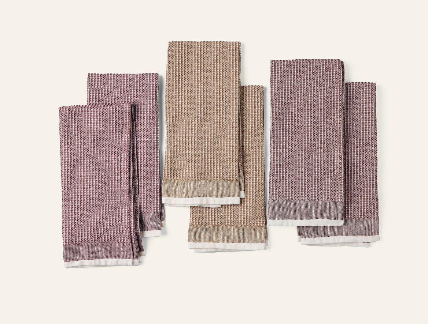 Coyuchi Waffle Kitchen Towel Set in mauve, taupe, and charcoal waffle-weave linen, flat lay.