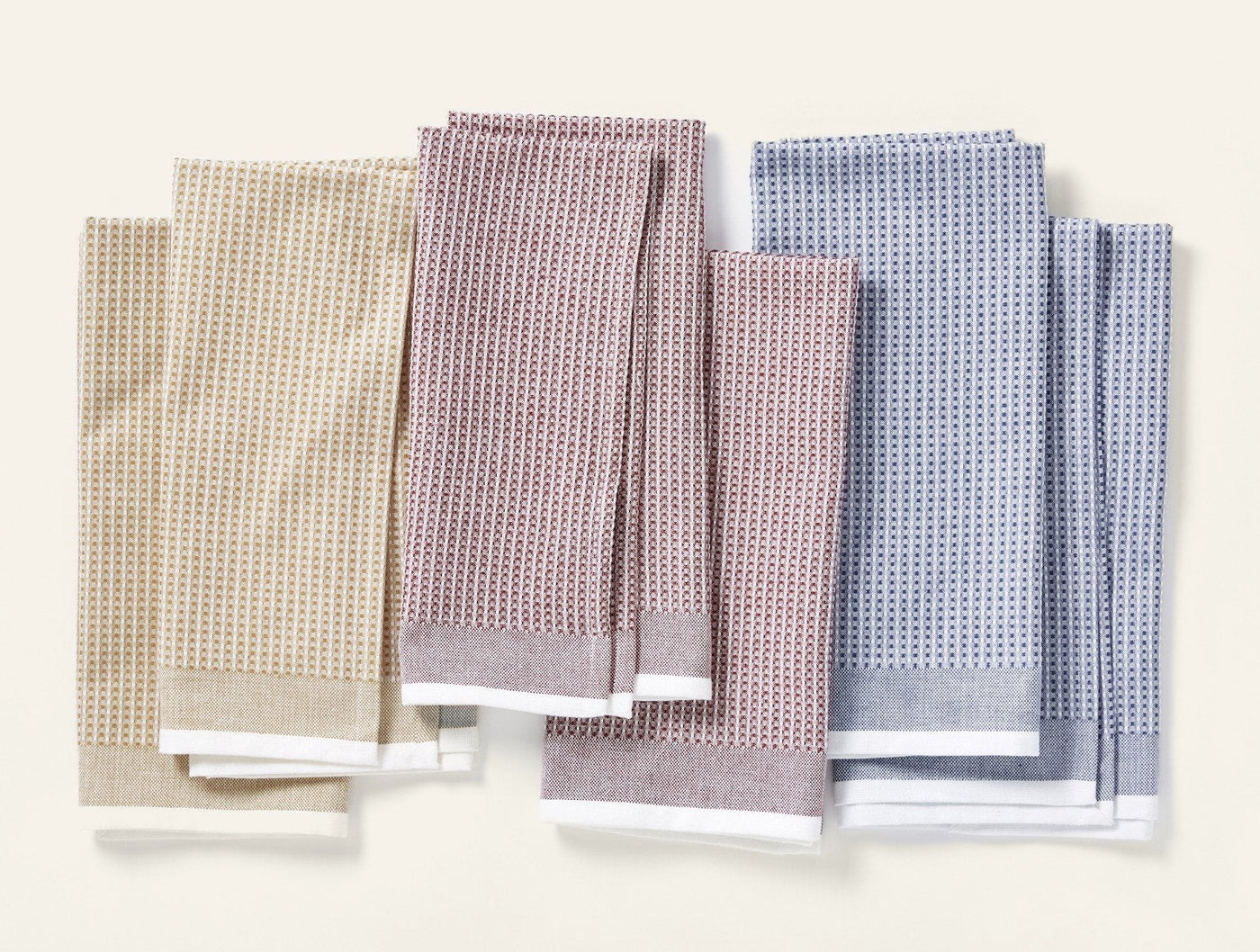 Coyuchi waffle kitchen towel sets in sage, mauve, and blue, fanned flat on white.