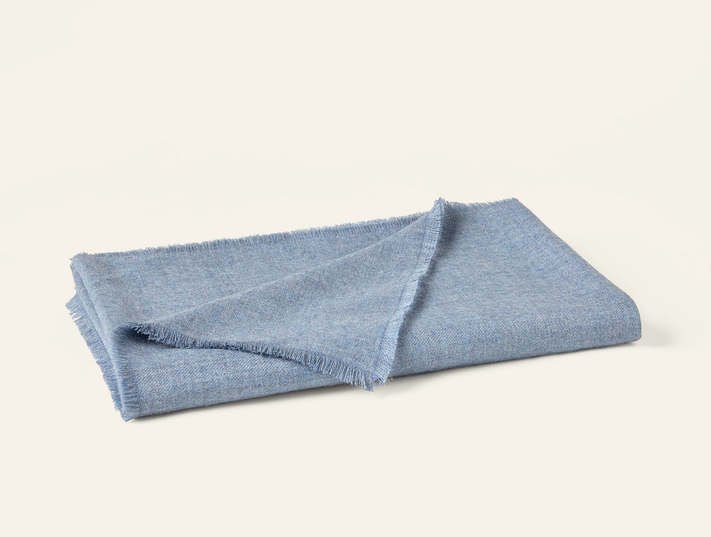 Coyuchi Pacaya Baby Alpaca throw in sky blue with fringe trim, folded flat.