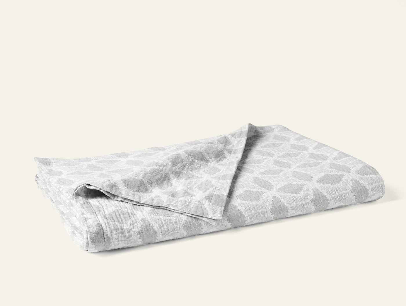 Folded Coyuchi Palomar blanket showing silver geometric honeycomb pattern on white ground.