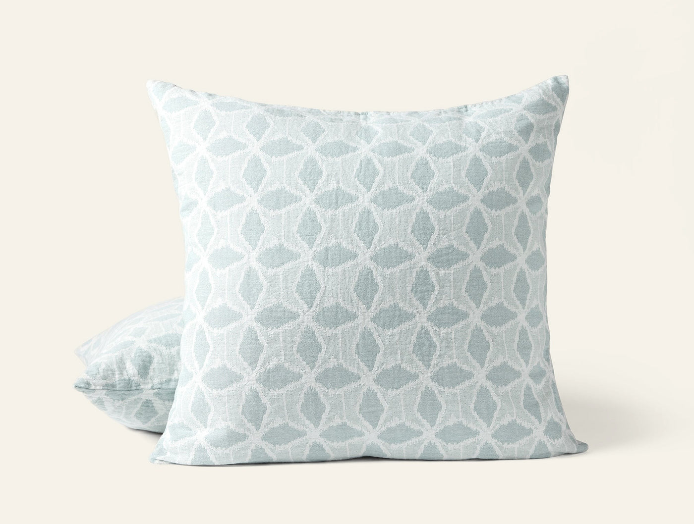 Close-up of Coyuchi Palomar sham in seafoam, geometric floral jacquard pattern, two shams stacked.