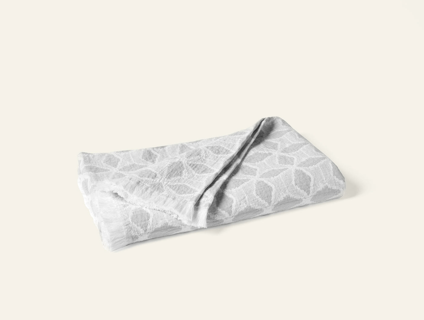 Folded Coyuchi Palomar throw in silver grey with geometric leaf jacquard pattern.