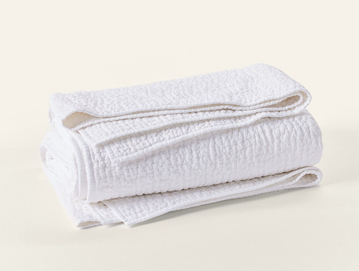 Coyuchi Pebbled Handstitched quilt in white, folded to show textured pebble weave.