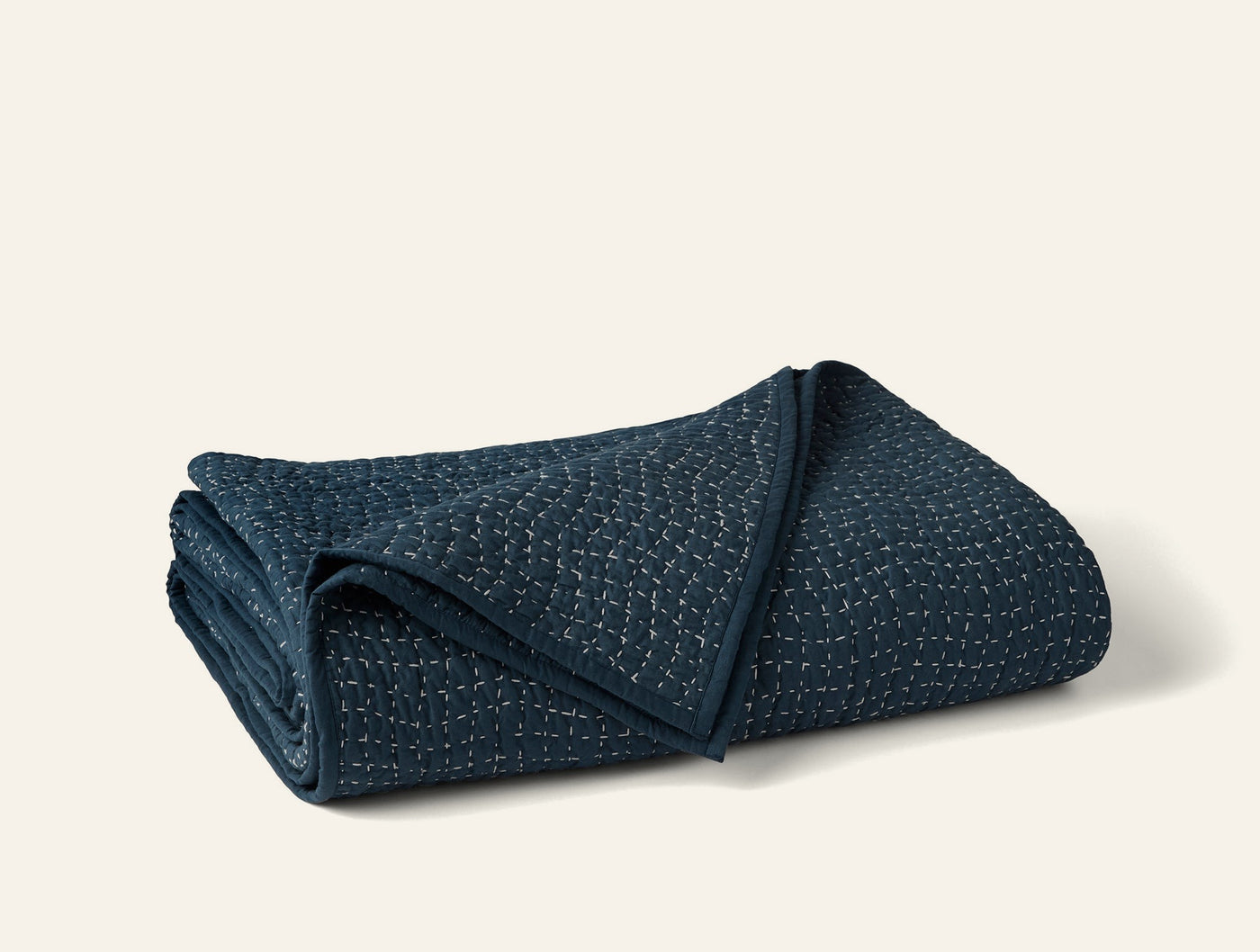 Coyuchi Pebbled Handstitched quilt folded, showing navy textured weave and stitched edges.