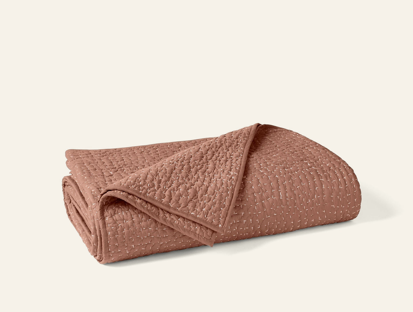 Coyuchi Pebbled Handstitched quilt folded, showing terracotta texture and handstitched detail.