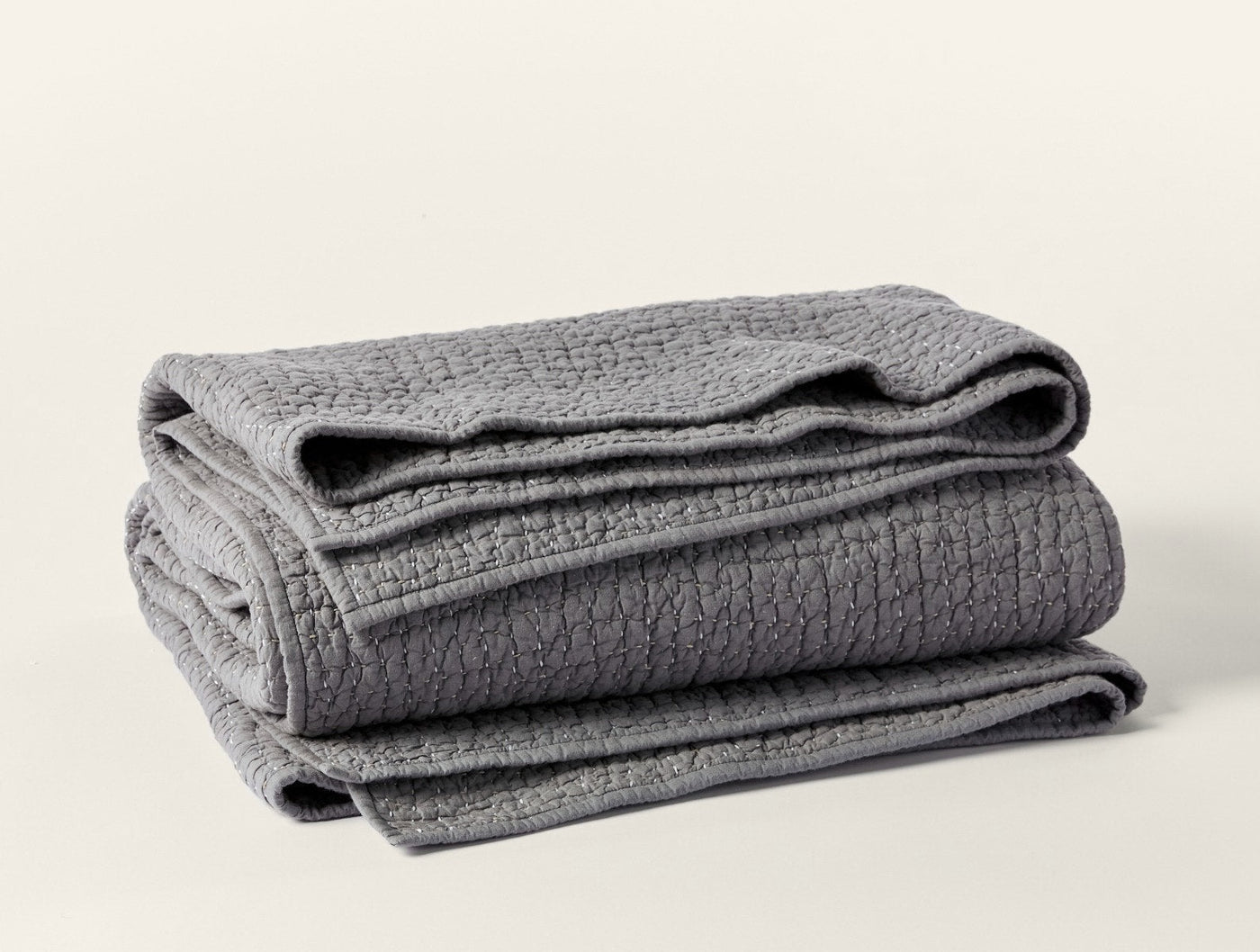 Folded slate grey Coyuchi quilt showing pebbled texture and handstitched detail.