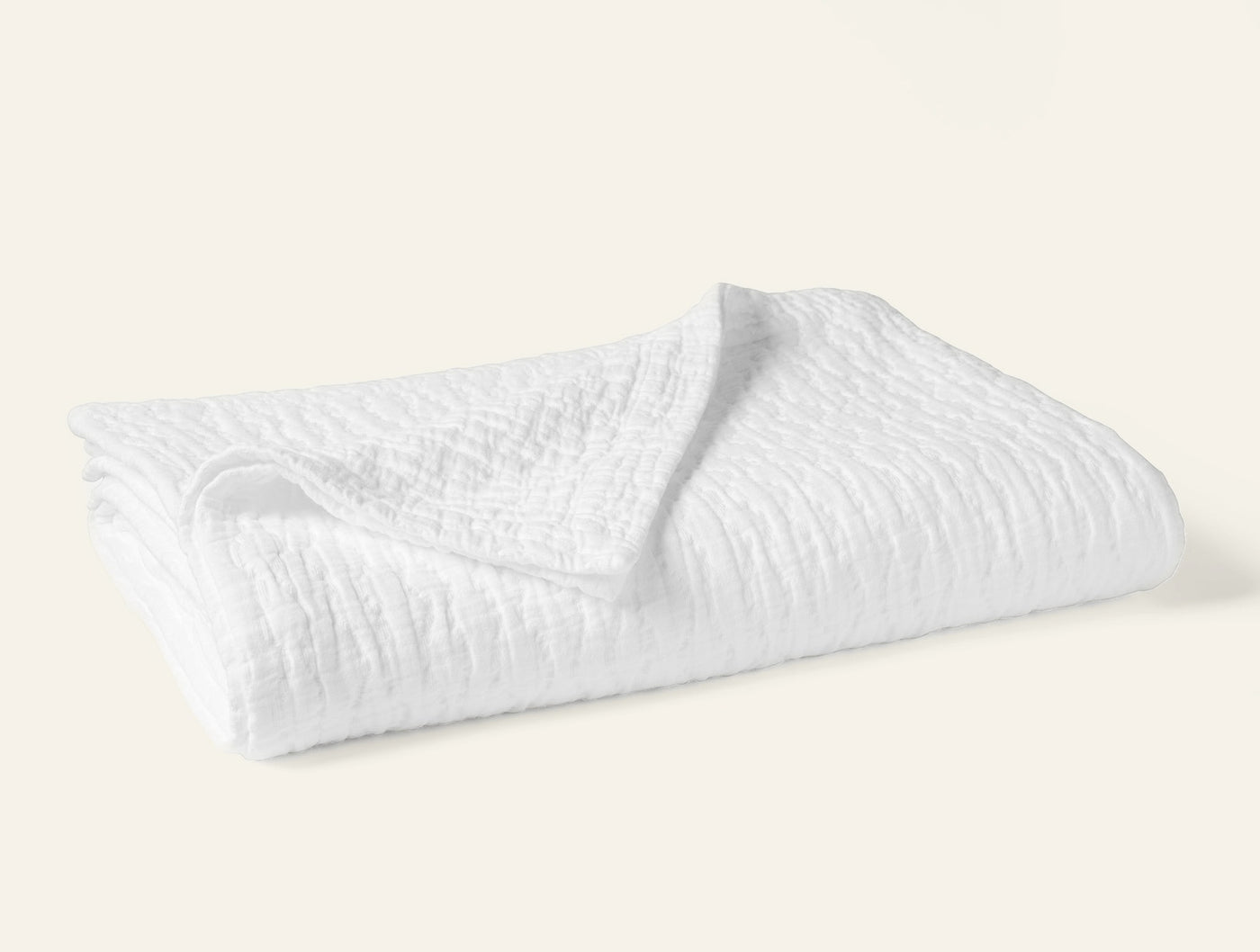 Coyuchi Pescadero Matelassé blanket in white, folded to show textured weave pattern.