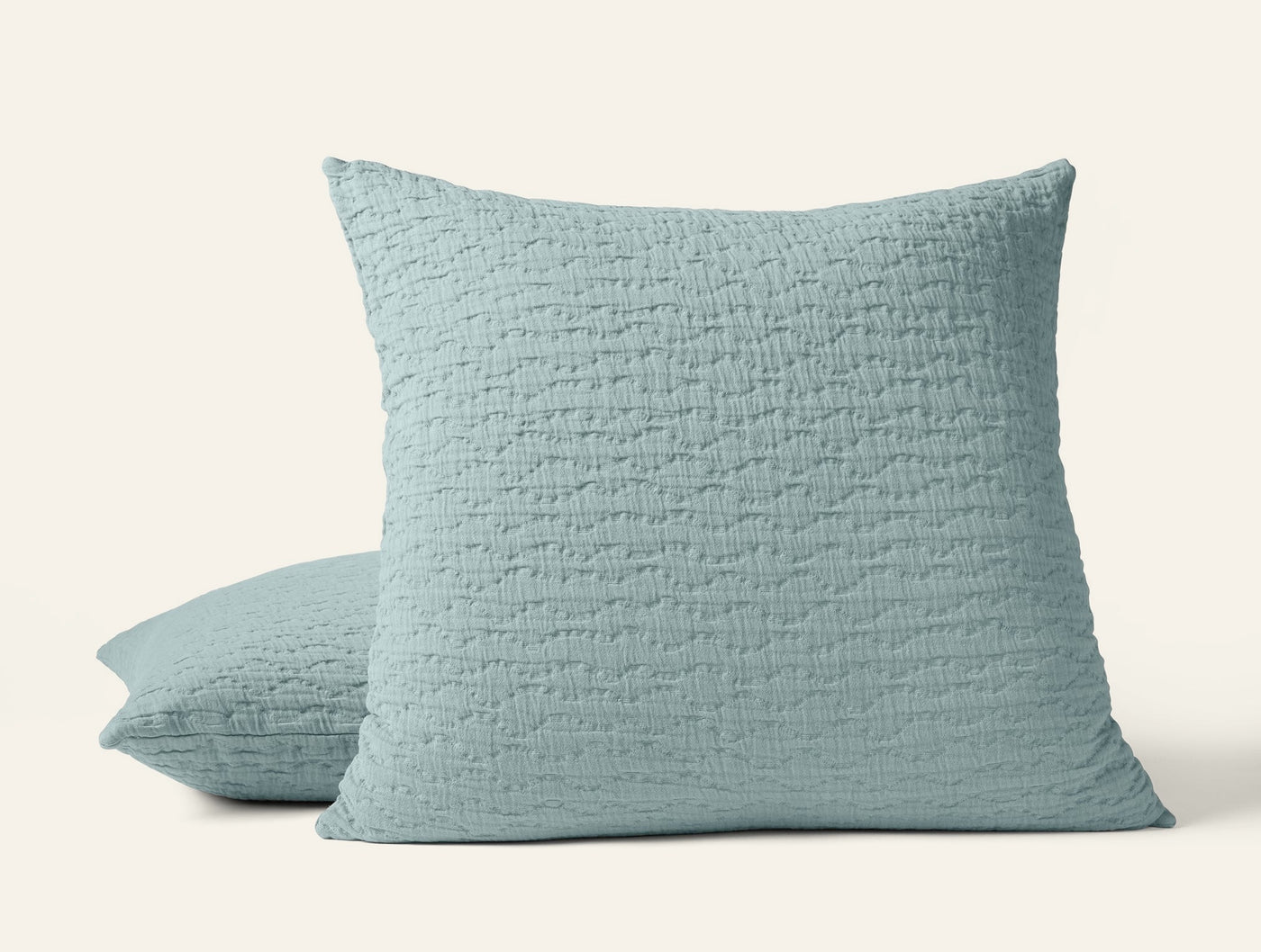 Seafoam matelassé pillow shams stacked, showing quilted linen texture.