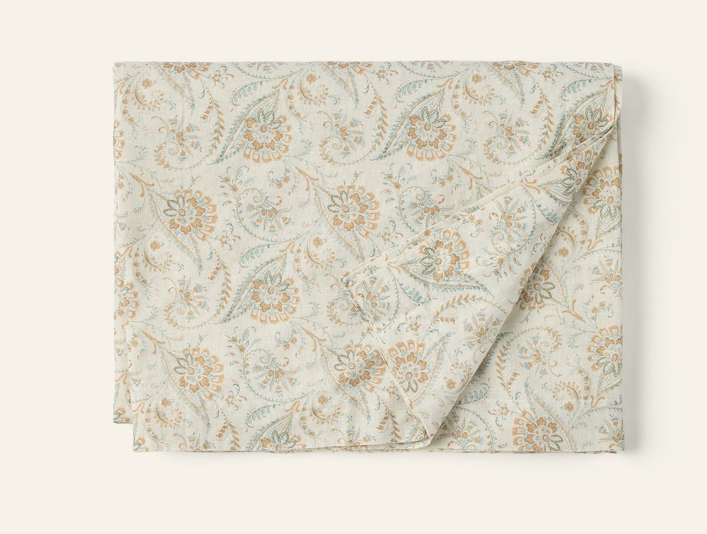 Coyuchi Ponderosa Print tablecloth in ivory with sage and amber floral print, folded flat.
