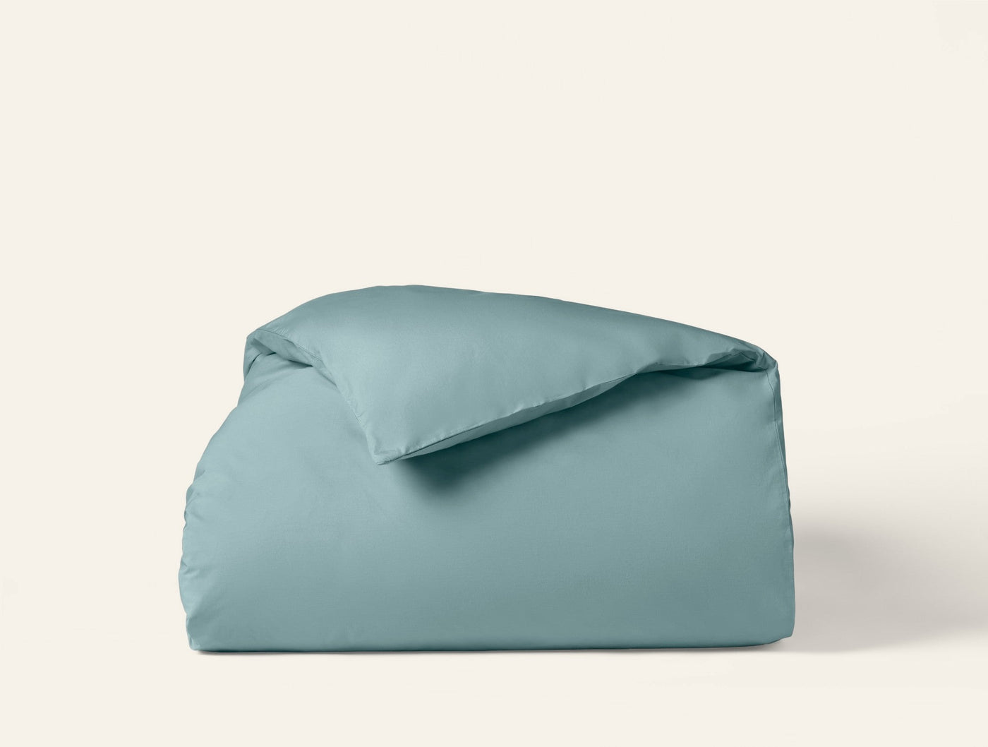 Coyuchi Refined Percale duvet cover folded neatly, shown in muted teal against a white background.