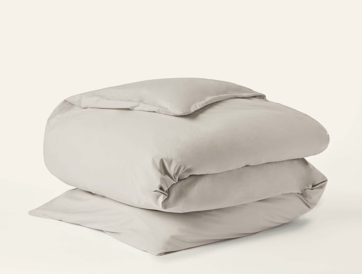 Coyuchi Refined Percale duvet cover folded neatly, shown in warm stone against white background.
