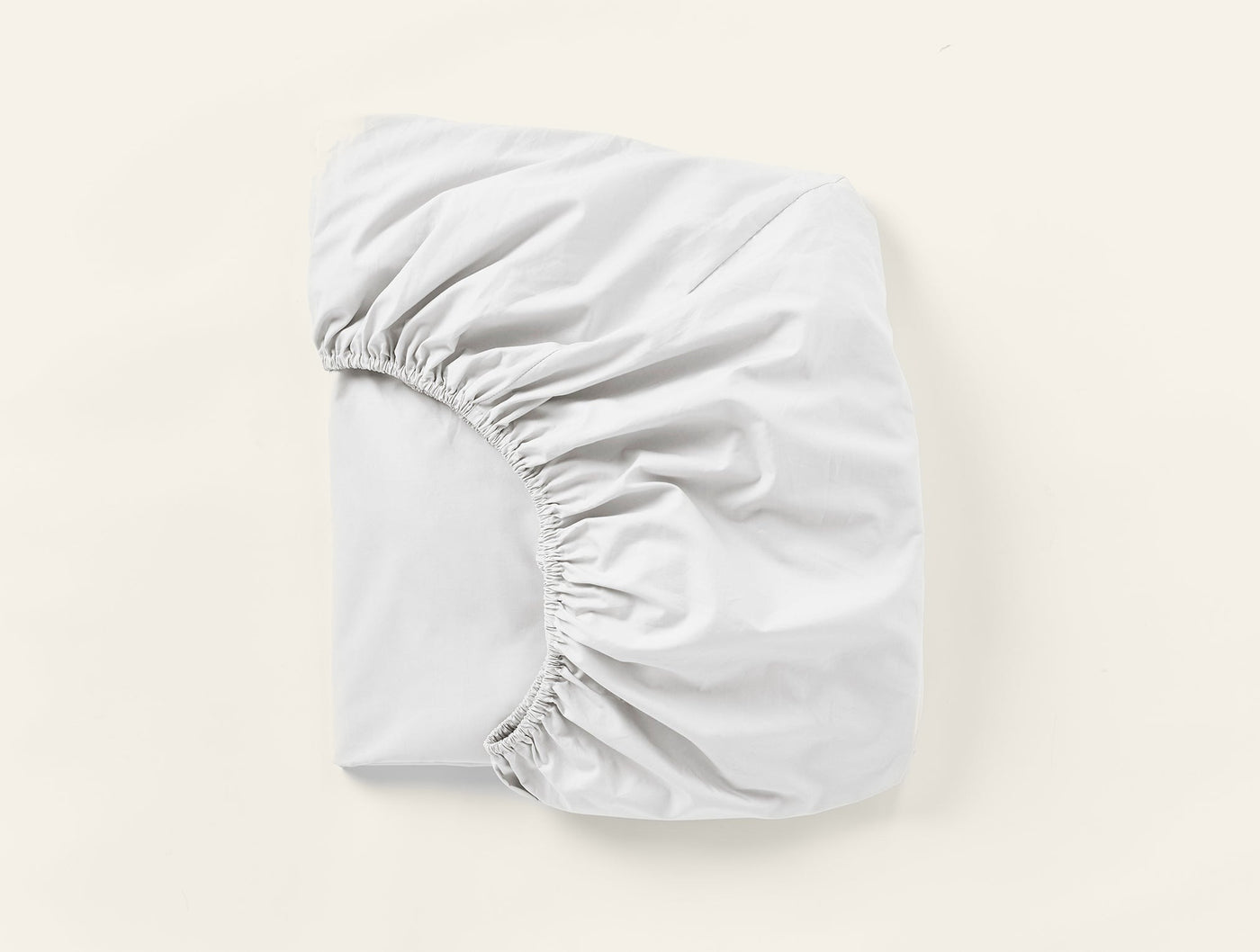 Coyuchi Refined Percale fitted sheet in white, folded to show elasticated corners.