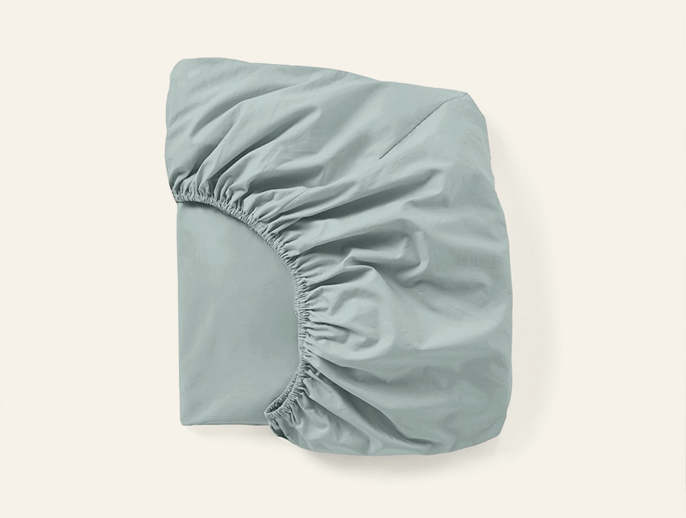 Coyuchi Refined Percale fitted sheet in sage, showing elasticated corners and smooth percale weave.